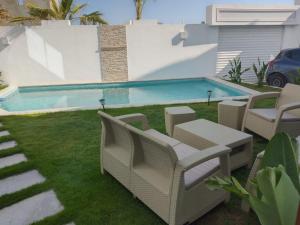 a yard with chairs and a swimming pool at Villa Nesrine in Hammamet Sud