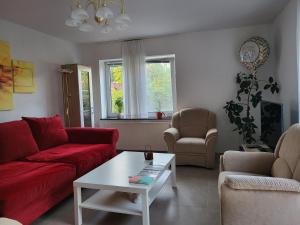 ein Wohnzimmer mit einem roten Sofa und einem Tisch in der Unterkunft Ferienhaus La Farfalla in Munster im Heidekreis
