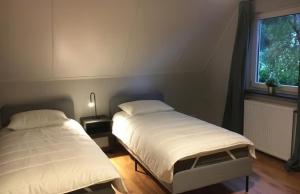 two twin beds in a room with a window at Luxe boshuis in hartje Drenthe in Spier
