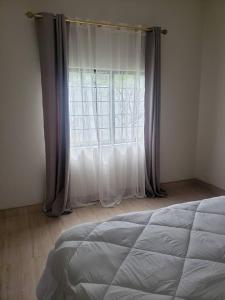 a bedroom with a bed and a window with curtains at A Home Away From Home in Lusaka