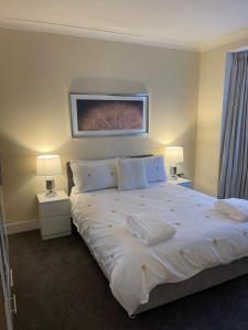 a bedroom with a large white bed with two lamps at 4 Bed Family Home in Woodford Green