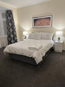 a bedroom with a large bed with two night stands and two lamps at 4 Bed Family Home in Woodford Green