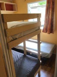 Ce lit superposé se trouve dans un dortoir doté d'une fenêtre. dans l'établissement Camping Parc des Roches-Mobilhome, à Saint-Chéron
