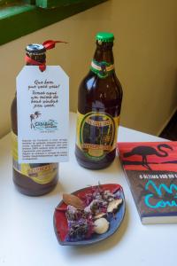 dos botellas de cerveza y un plato de comida en una mesa en Casarão das artes hospedaria en Cumuruxatiba