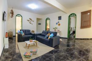uma sala de estar com dois sofás azuis e uma mesa em Casarão das artes hospedaria em Cumuruxatiba