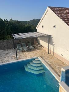 een zwembad met een pergola naast een huis bij Vacation house with pool in Ljubitovica
