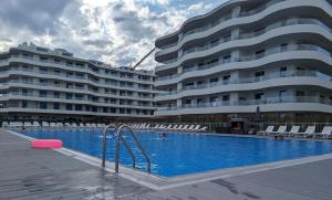 a swimming pool in front of a large building at Sunrise Apartament in Rogowo