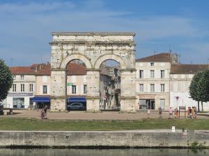 a large stone building with an arch in a city at L'Atelier 7 in Saintes