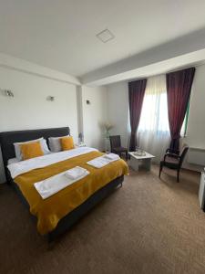 ニクシッチにあるGarni hotel Niksicの大きなベッドと椅子が備わるホテルルームです。