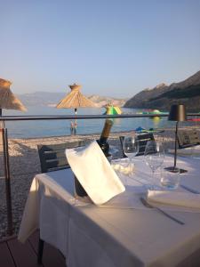 a table with wine glasses and a view of the beach at Hotel Dobrovit in Baška