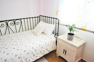 ein kleines Schlafzimmer mit einem Bett und einer Pflanze auf einem Nachttisch in der Unterkunft GALIHOST - Casa con jardín en Cambados in Cambados