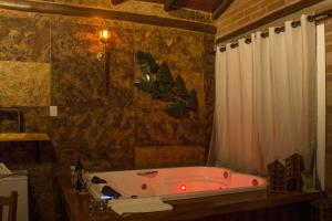 a bathroom with a tub with a shower curtain at Pousada Chales Rancho Caipira in Santo Antônio do Pinhal