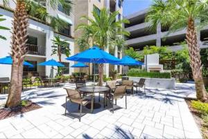 a patio with tables and chairs and blue umbrellas at Blooming Journey in Tampa Bay! in Tampa