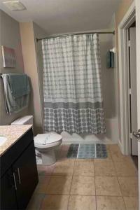a bathroom with a toilet and a shower with a shower curtain at Blooming Journey in Tampa Bay! in Tampa