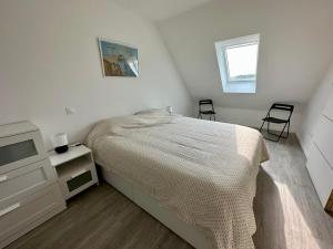 een witte slaapkamer met een bed en een televisie bij La Belle Envolée in Wissant