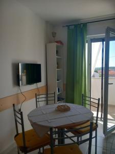 una sala da pranzo con tavolo, sedie e TV di Apartment Red wine a Ližnjan (Lisignano)