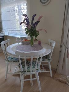 a white table with a vase of flowers on it at Cozy centre apartment KKE in Ventspils +5 photos