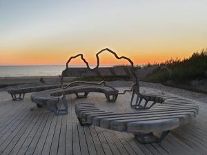 two benches on the beach with the sunset in the background at Cozy centre apartment KKE in Ventspils