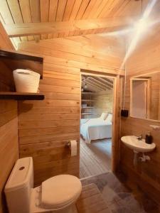 uma casa de banho com um WC, um lavatório e uma cama em La Peña Cabins en Ebéjico em Ebéjico