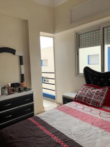 um quarto com uma cama, uma cómoda e uma janela em Découvrez la magie d'El Jadida depuis notre appartement de charme em El Jadida