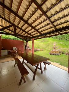 une table et des bancs en bois sous une pergola en bois dans l'établissement Casa de Serra Guaramiranga, à Guaramiranga