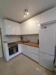 a kitchen with white cabinets and a refrigerator at Apartman Mila in Split
