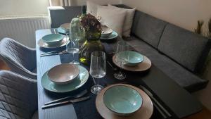 une table avec des assiettes et des verres à vin sur un canapé dans l'établissement Pohorje Pearl Lux, 2-Floor Apartment, Ski in, à Hočko Pohorje