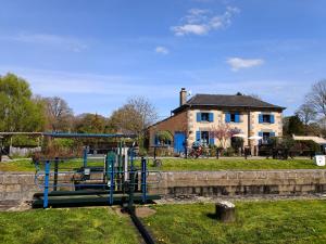 a park with a playground in front of a house at Ille Flottante, Maison éclusière et hébergements insolites sur le canal in Hédé