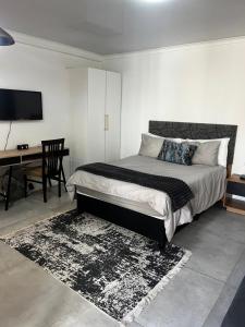 1 dormitorio con 1 cama y escritorio con TV en Lagoon Lodge en Ciudad del Cabo