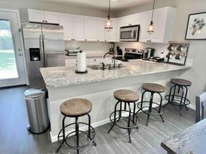 a kitchen with three bar stools and a counter at San Sebastiáns Hideaway - Modern with Group Friendly Amenities just minutes from Downtown and St Augustine Beach in Saint Augustine