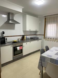 une cuisine avec des placards blancs et une table avec un chiffon de table dans l'établissement Apartamento Duplex O capitán, à A Guarda