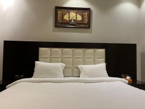 una camera da letto con un grande letto bianco con testiera nera di Darina Serviced Apartments a Riyad Altre 26 foto