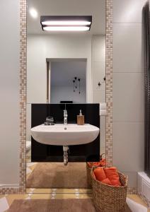 uma casa de banho com um lavatório branco e um espelho. em Stilingi šaulio skulptūros apartamentai em Druskininkai