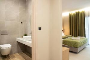 a bathroom with a bed and a toilet and a sink at Olympus Suites in Paralia Panteleimonos