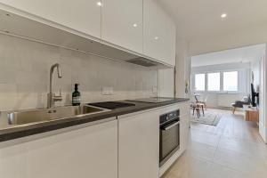 uma cozinha branca com um lavatório e um fogão em CityStay full brand new appartement 3 bedrooms 5min to Paris em Bagnolet