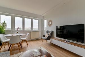 uma sala de estar com uma grande televisão e uma mesa e cadeiras em CityStay full brand new appartement 3 bedrooms 5min to Paris em Bagnolet