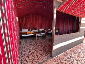 a red room with two beds and a mirror at Wadi Rum Orion Camp in Wadi Rum