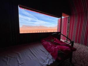 a bedroom with a bed and a large window at Wadi Rum Orion Camp in Wadi Rum