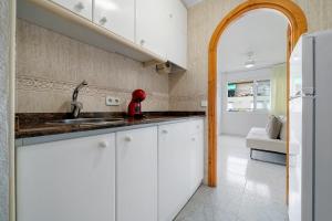 a kitchen with white cabinets and a sink at Hauzify I Apartament Estrella in Platja  d'Aro