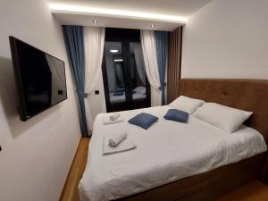 a bedroom with a white bed with blue pillows and a television at Zlatibor luxury residence, near the center in Zlatibor +12 photos
