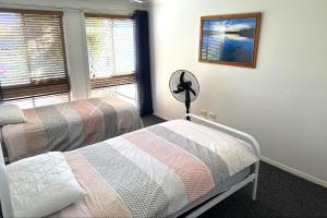 a bedroom with two beds and a fan and a window at LAKE HOUSE ON ELOUERA in Forster