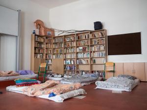 a room with several beds in front of a book shelf at Budget Hostel in Prague