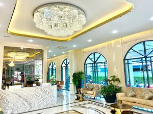 a lobby with a large chandelier and chairs at Banbua Grand Udon in Udon Thani