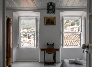 a bedroom with two windows and a table in it at Gelhaus 1935 in Hydra
