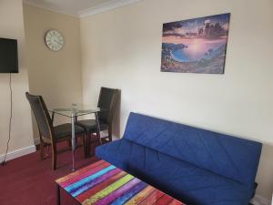 a living room with a blue couch and a glass table at Comfy one bedroom flat in Tilehurst