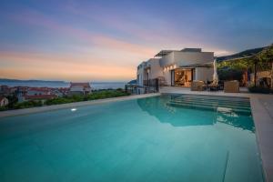 a swimming pool in front of a house at Luxury Villa Envivo Komiža with heated pool and professional gym in Komiža