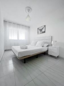 ein weißes Schlafzimmer mit einem Bett und einem Nachttisch in der Unterkunft Residencial Portonovo in Portonovo