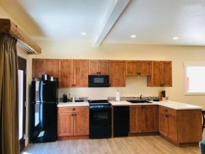 eine Küche mit Holzschränken und einem schwarzen Kühlschrank in der Unterkunft Bluff Dwellings Resort in Bluff
