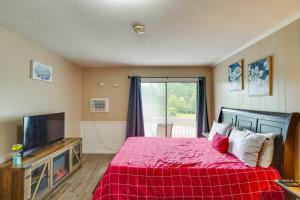 ein Schlafzimmer mit einem Bett mit einer roten Decke und einem TV in der Unterkunft New River Gorge Vacation Rental with Balcony! in Fayetteville