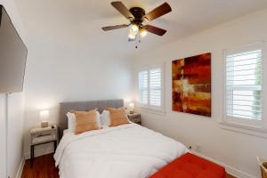 a bedroom with a white bed with a ceiling fan at Belmont Shore Stunner in Long Beach